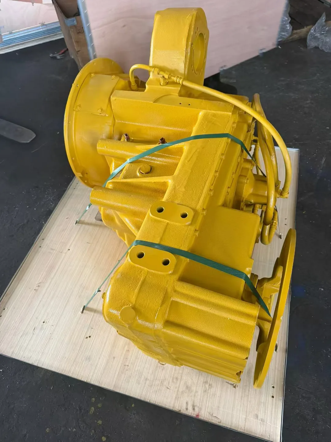 Yellow construction machinery transmission assembly on a wooden base