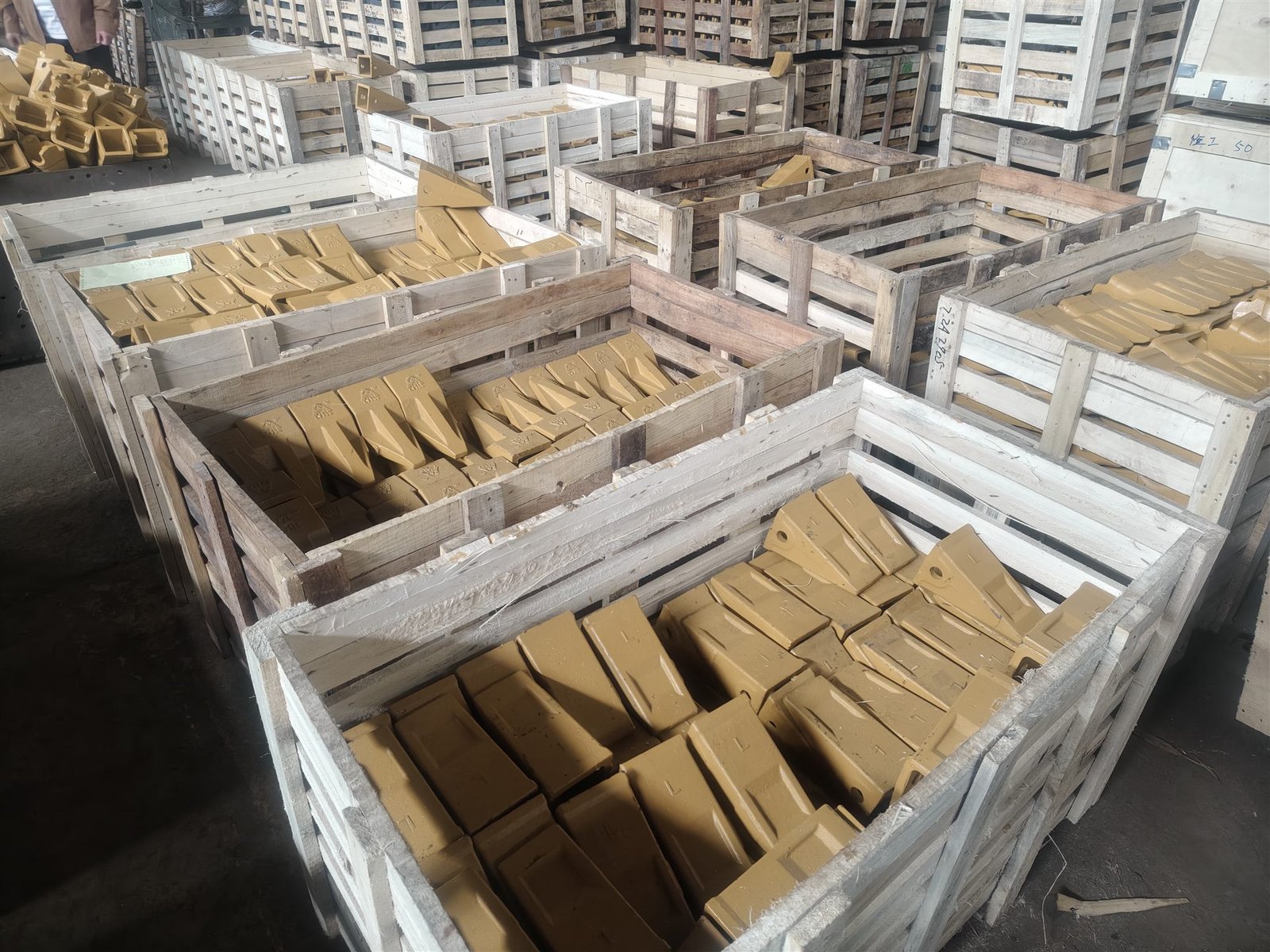 Replacement excavator bucket teeth arranged in wooden packing crates